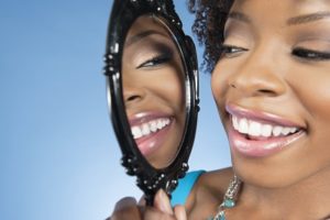 Woman examining her teeth in a mirror.